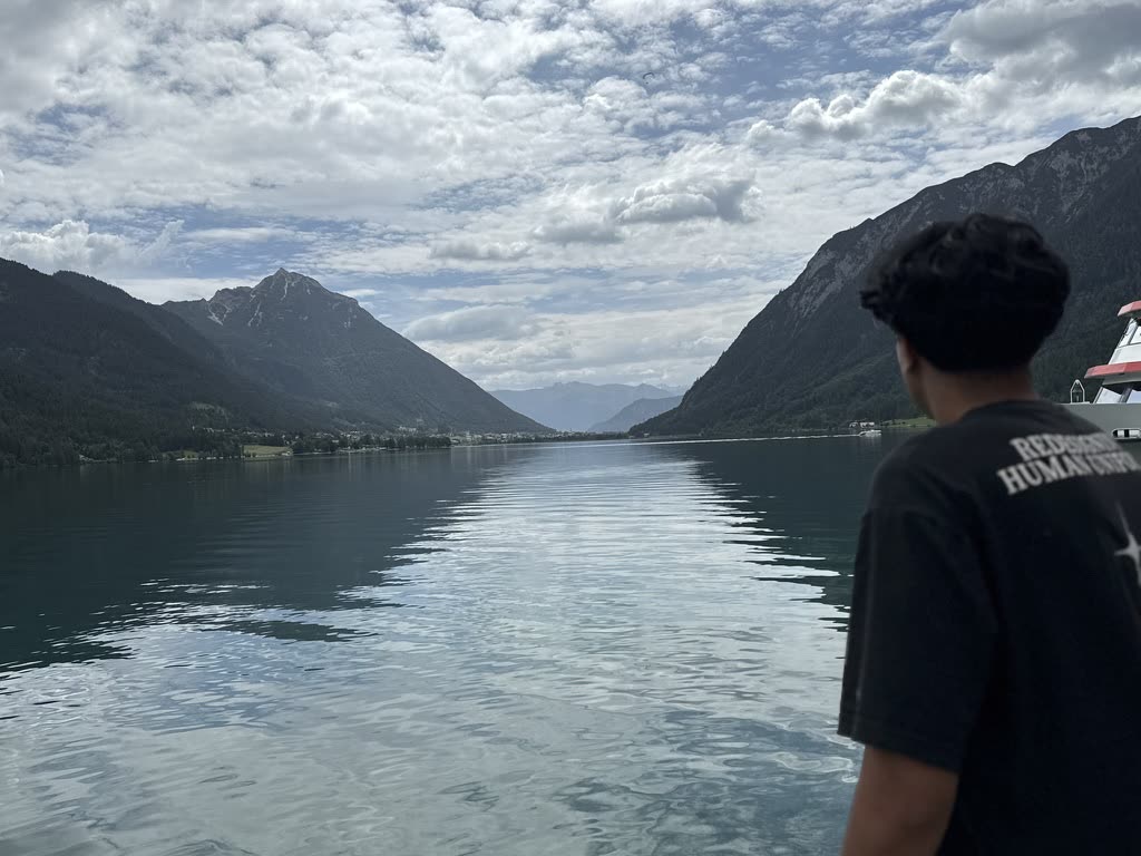 Pranil looking across a calm alpine lake toward the mountains near Interlaken