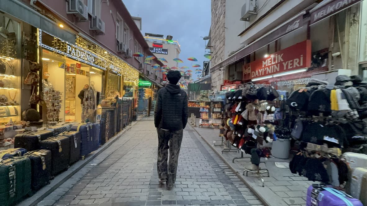 Pranil walking down an Istanbul market street lined with shops and colorful umbrellas