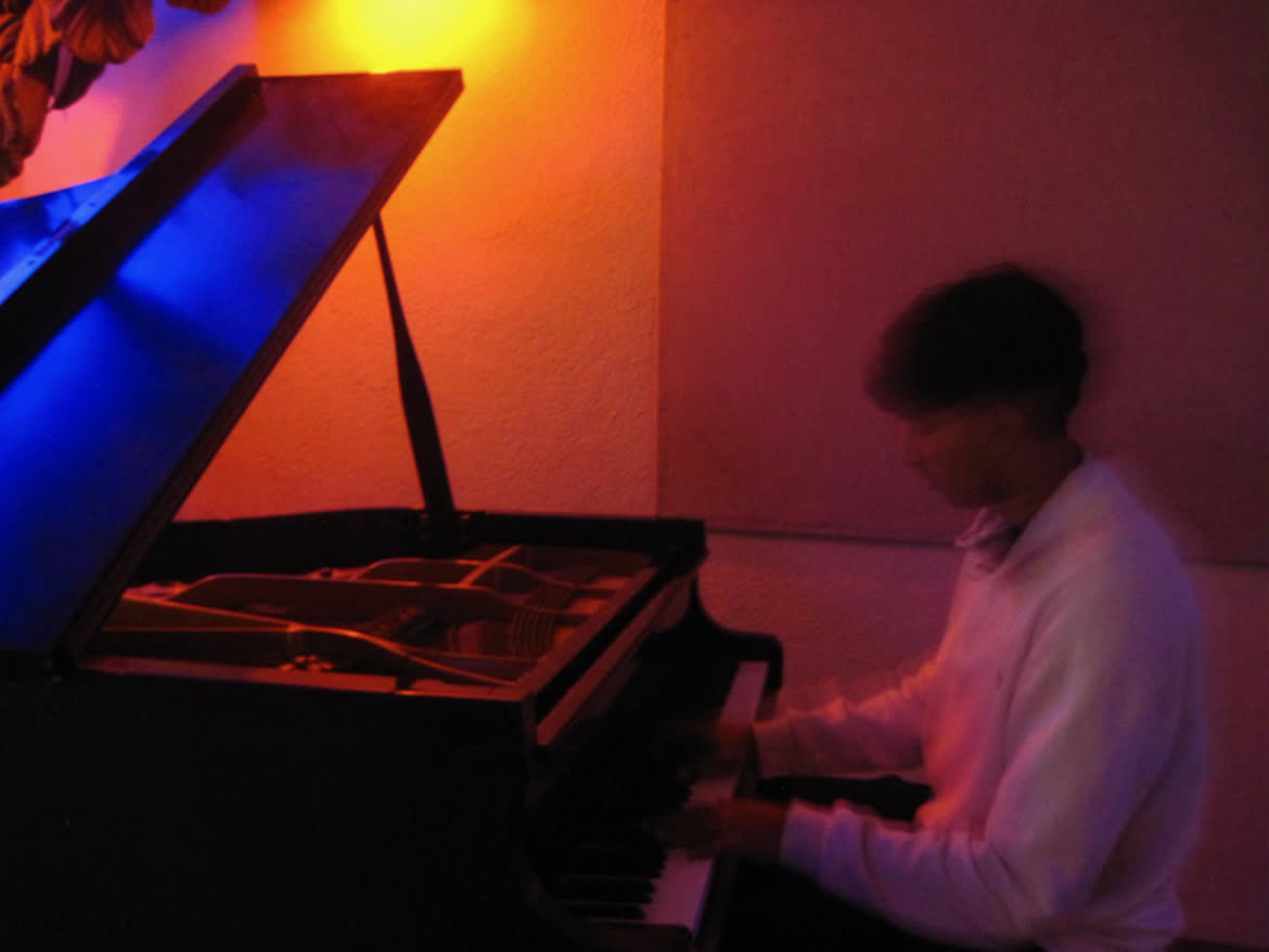 Playing a grand piano under colorful stage lights