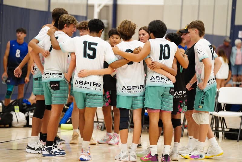 Aspire Volleyball Club team huddled together on the court