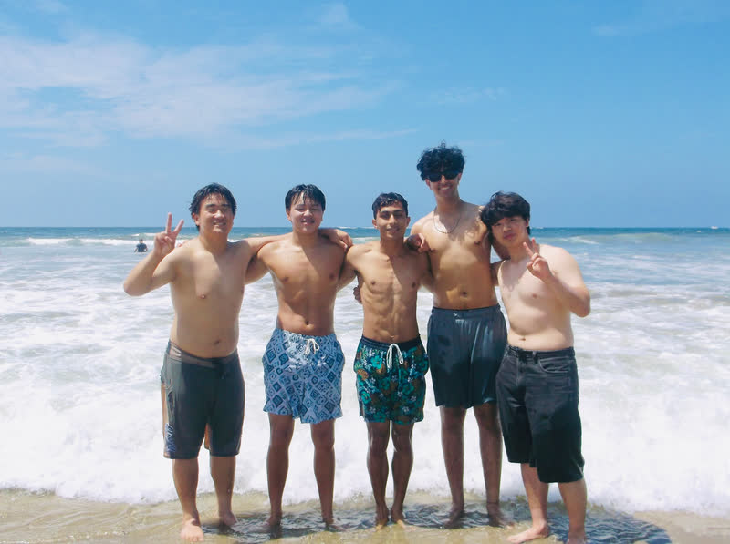 Friends standing together at the edge of the ocean