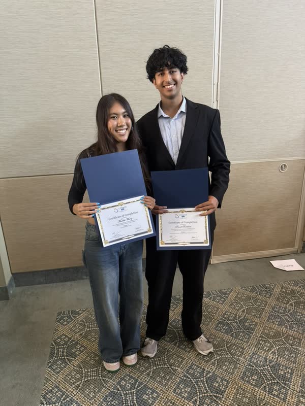 Two COSMOS students holding completion certificates