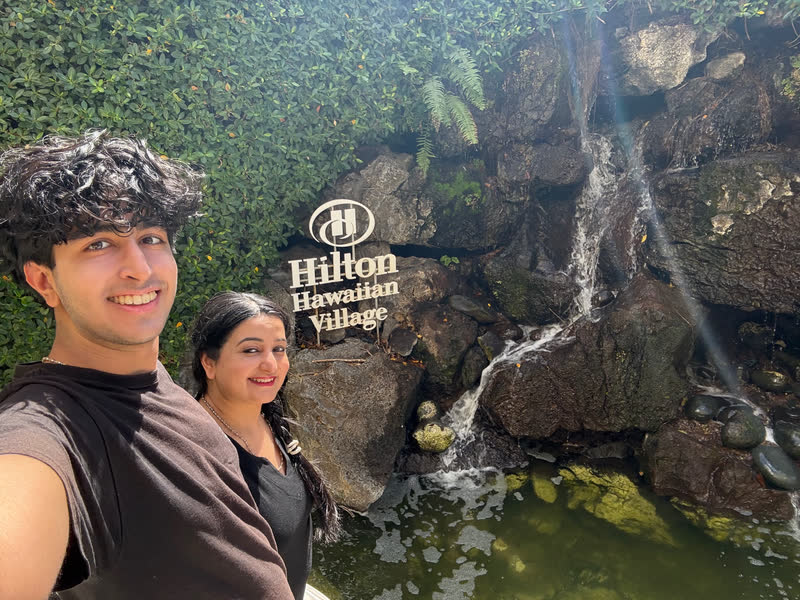 Pranil taking a selfie beside the Hilton Hawaiian Village waterfall sign