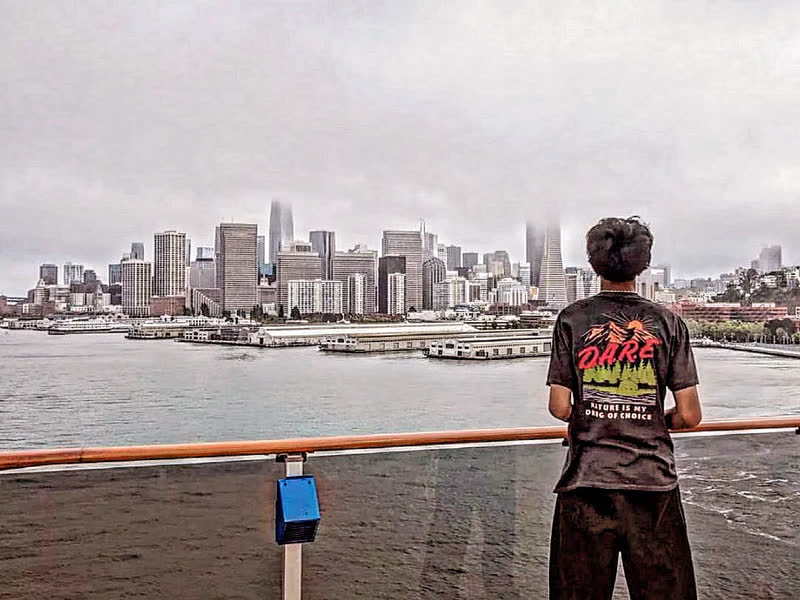 Pranil in a DARE shirt looking toward the San Francisco skyline from a ship