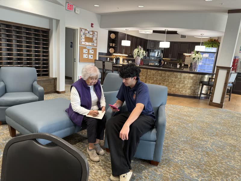 Helping an older adult with a smartphone in a community lounge