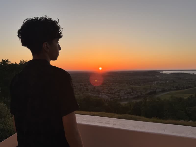 Pranil silhouetted against a sunset over a valley