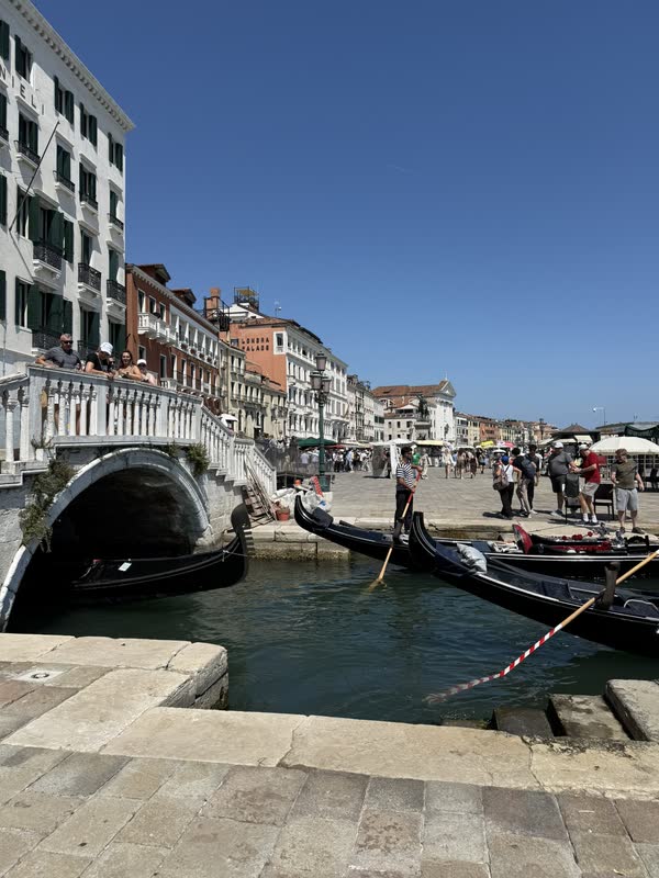 Gondolas passing beneath a stone bridge along a Venice canal