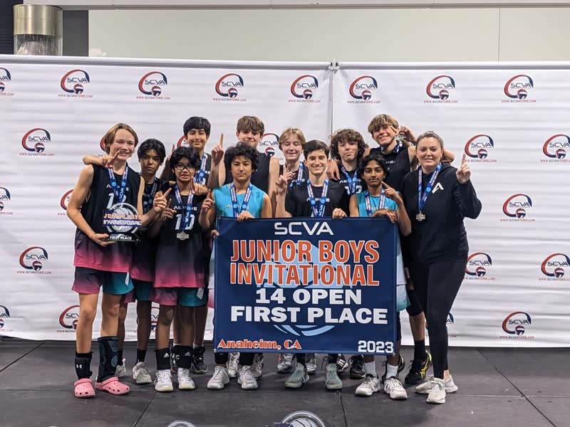 Youth volleyball team posing with a first-place tournament banner